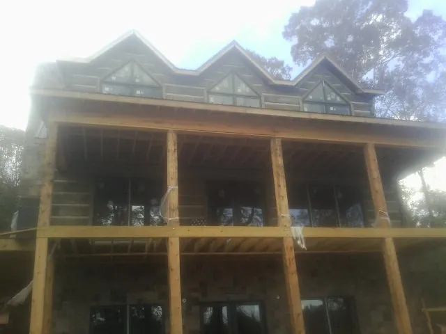 Dormers and porch framing on a large log home under construction — Roof Coating work by our crew in University Park