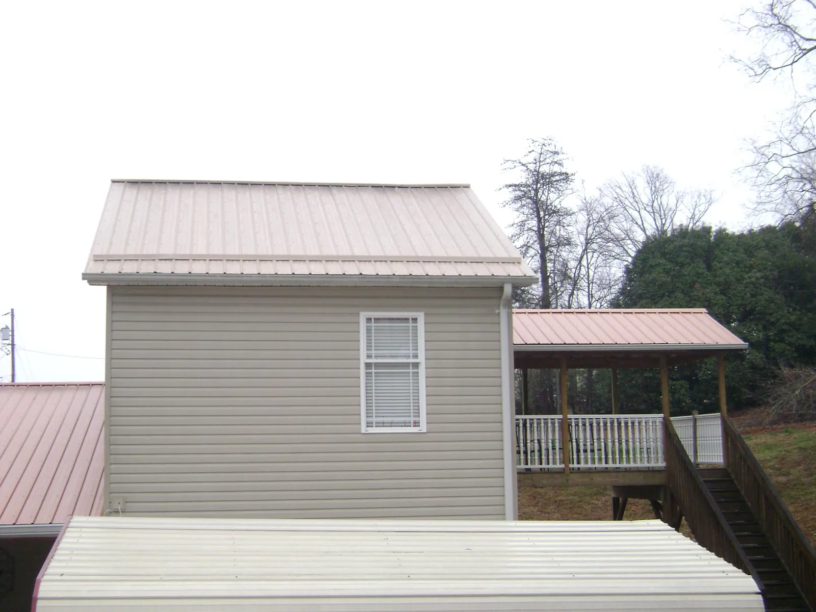 Tan metal roofs on a two story addition and attached porch, from a Roof Replacement job in University Park